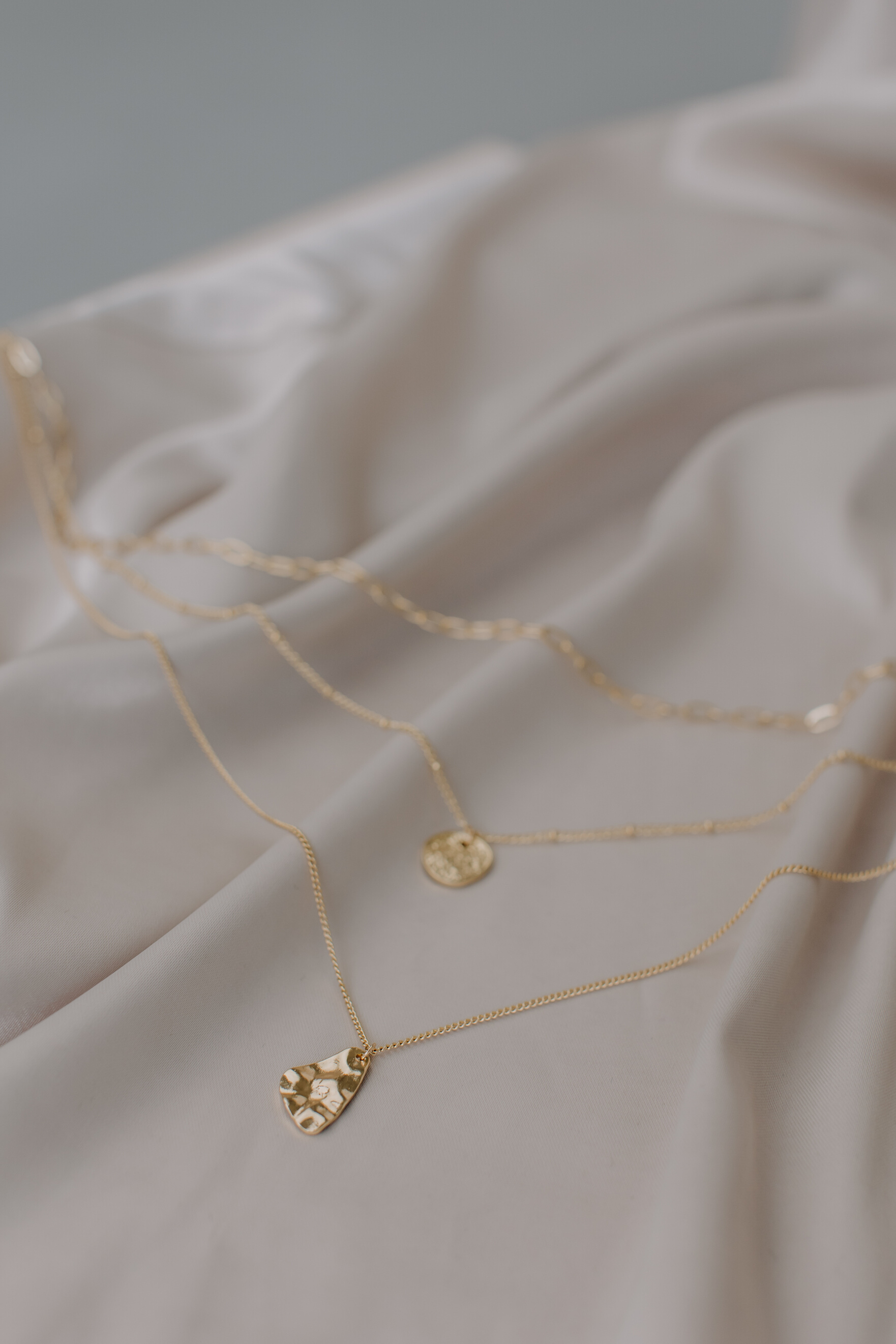 Gold Necklaces with Pendants on White Fabric
